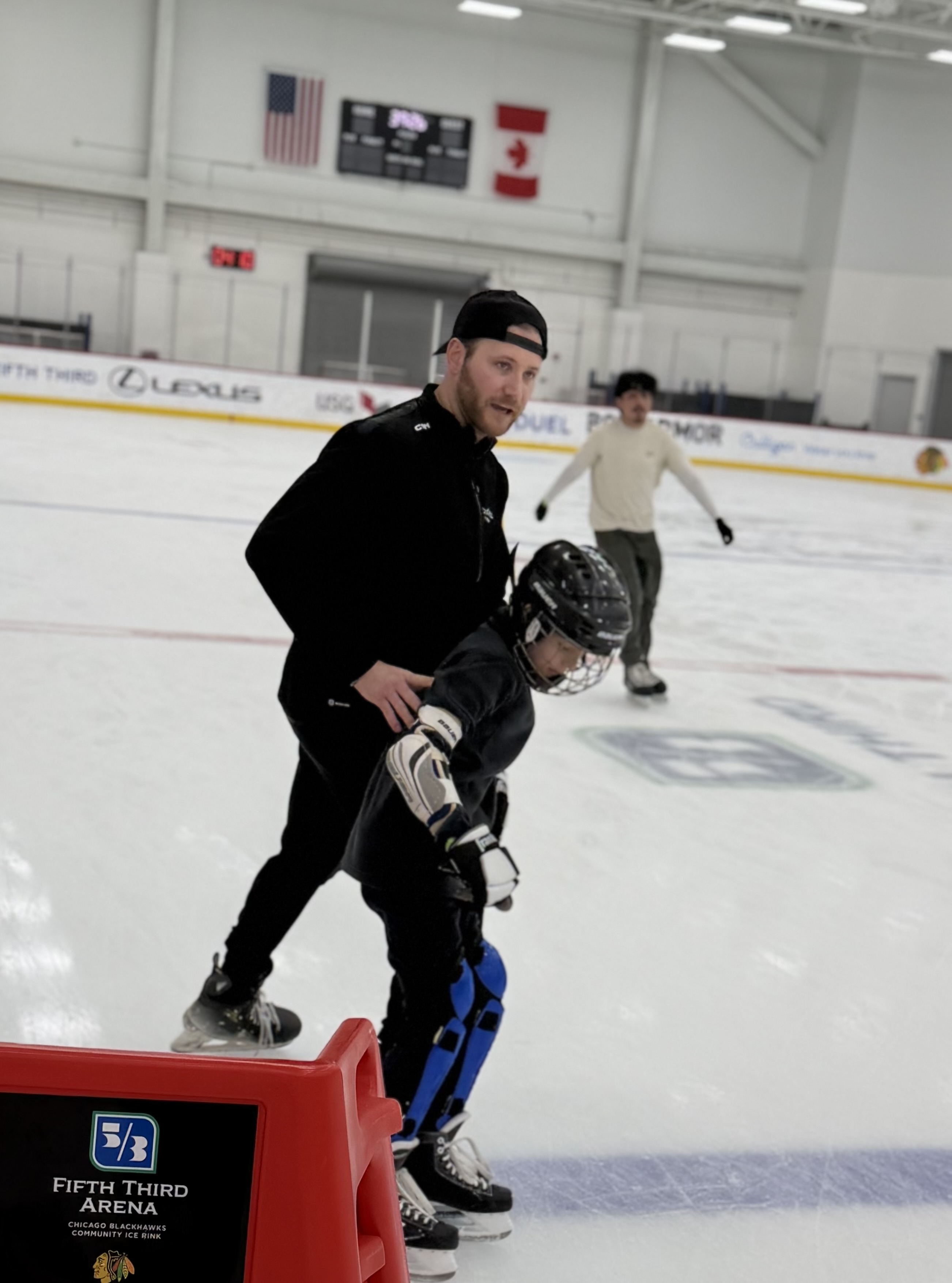 Ryan Devine coaching a young player 1-on-1 at a Chicago Blackhawks community rink